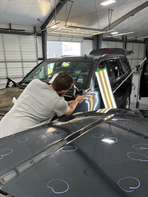 A man working on the hood of a car.